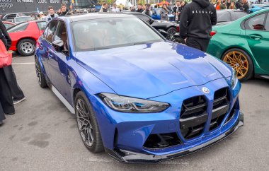 Canlı mavi BMW M3 yarışma sedanı belirgin büyük dikey böbrek ızgarası, agresif ön ayırıcı ve siyah aerodinamik elementlere sahiptir.