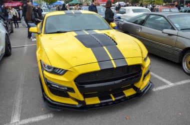 Çarpıcı sarı Ford Mustang Shelby GT500 ile ağır modifiye edilmiş, büyük, agresif ön ızgara, kaput menfezleri, ve koyu siyah yarış çizgileri ile