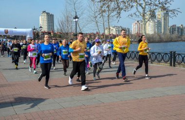 Güneşli bir günde şehrin deniz manzaralı bir bölgesinde düzenlenen organize bir maraton etkinliğine aktif olarak katılan koşucular, sağlık ve zindeliği destekliyor.