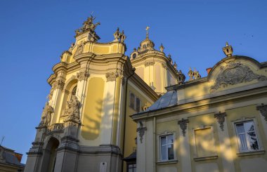 Aziz Georges Katedrali 'nin ön cephesi, süslü heykeller ve derin mavi gökyüzü ile çelişen sıcak güneş ışığıyla aydınlatılmış kubbelerle süslenmiştir. Barok-rokoko mimarisinin başyapıtı. Lviv, Ukrayna