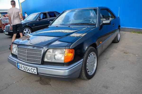 Siyah 1995 Mercedes Benz W124 coupe klasik Mercedes-Benz ızgarası ve büyük farlarıyla zarif, sütunsuz coupe tasarımı sergiliyor.