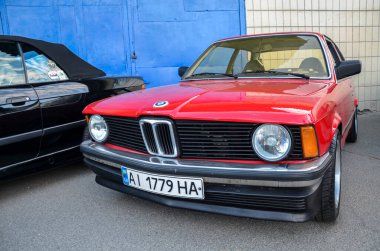  Kırmızı klasik BMW E21, BMW 2002 'nin ardılı oldu ve 3 seriyi kompakt yönetici spor sedanları için bir kriter olarak kurdu.