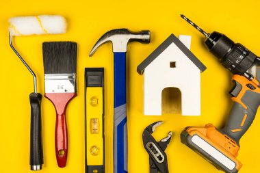 Beyaz Saray oyuncakları ve inşaat aletleri. Yejow arka planında kopya alanı. Emlak konsepti, yeni ev onarım konsepti.