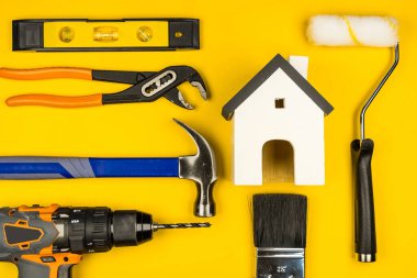 Beyaz Saray oyuncakları ve inşaat aletleri. Yejow arka planında kopya alanı. Emlak konsepti, yeni ev onarım konsepti.