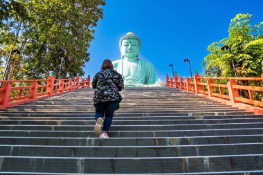 Lampang, Tayland - 19 Aralık 2022: Asyalı kadın turist, Lampang Tayland 'daki Wat Doi Phra Chan-in Budist tapınağının Büyük Buda (Daibutsu) bronz heykelini gezip geziyor..