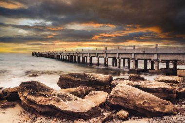Tranquil Beauty: Pier Köprüsü denize açılıyor, Tayland 'ın Doğu Adası' ndaki Rocky Shores 'ı gün batımında kucaklıyor.