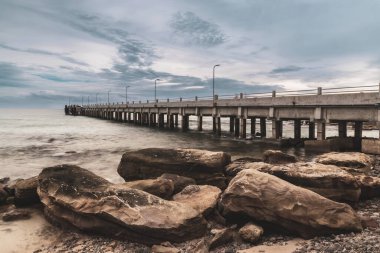 Tranquil Beauty: Pier Köprüsü denize açılıyor, Tayland 'ın Doğu Adası' ndaki Rocky Shores 'ı gün batımında kucaklıyor.