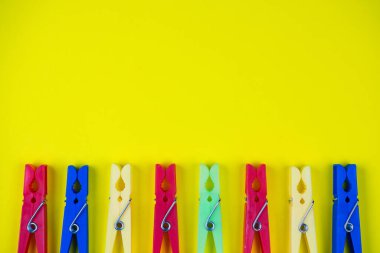 Sarı arka planda çok renkli mandallar var. Metin için boşluk