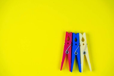 Sarı arka planda çok renkli mandallar var. Metin için boşluk