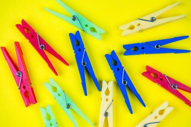 Sarı arka planda çok renkli mandallar var. Metin için boşluk