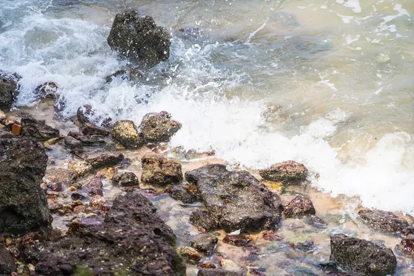 stock image Sea waves hit the rocks hit by sunlight.