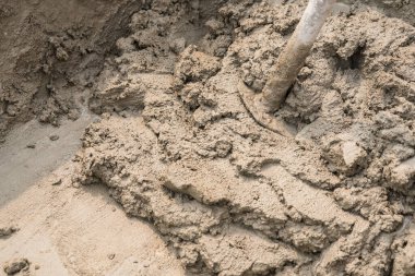 Çimento ile taşları karıştır. Arka plandaki büyük kovanın içinde çapa sızıntısı var.