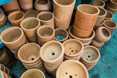 Bahçe bakkalında satılan kilden saksı, bahçe malzemeleri, arka planda bir yığın ağaç kabı.