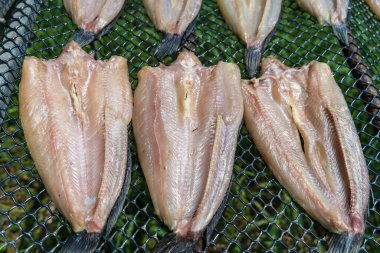 Stack of dried fish on a net clipart