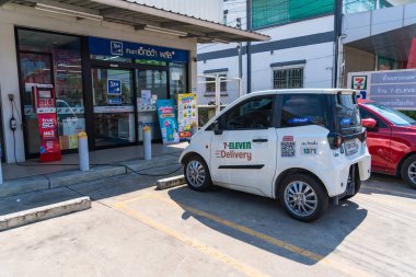 Bangkok, Thailand - June 21, 2024 :A white electric vehicle parked at a 7-Eleven convenience store in Thailand. The 7-Eleven store also offers delivery services at Bangkok Thailand. clipart