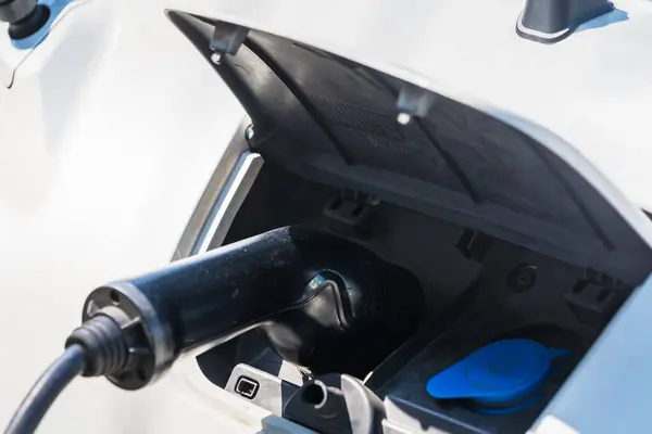 stock image electric vehicle charging port with a charging plug inserted. The blue symbol on the cap indicates where to plug in. This image highlights the technology of electric vehicles and the recharging process.