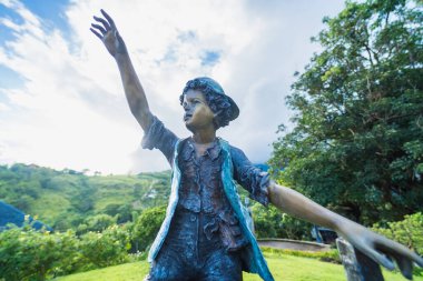 Bronze statues of two children sitting on a wooden fence, symbolizing the carefree and adventurous spirit of youth.