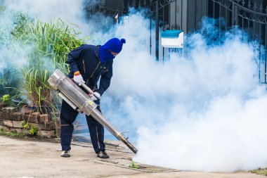 Bir sağlık çalışanı, şehir ortamında sivrisinek nüfusunu kontrol etmek için sis makinesi kullanır..