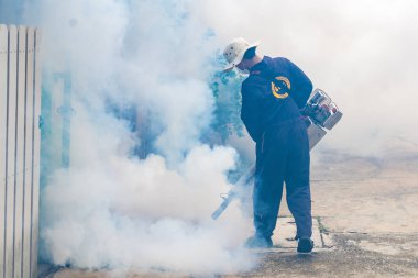 Bir sağlık çalışanı, şehir ortamında sivrisinek nüfusunu kontrol etmek için sis makinesi kullanır..