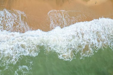 An aerial view of ocean waves crashing onto a sandy beach, showcasing the dynamic interaction between water and land. The image captures the natural beauty and rhythm of coastal landscapes. clipart