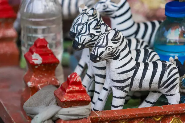Geleneksel el yapımı zebra heykelcikleri. Kırmızı süslemeler ve plastik şişelerle düzenlenmiş.