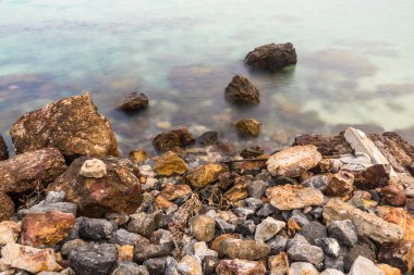 Huzurlu bir deniz manzarası. Antik kayalar sonsuz bir dansla nazik dalgalarla buluşur..
