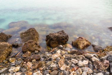 Huzurlu bir deniz manzarası. Antik kayalar sonsuz bir dansla nazik dalgalarla buluşur..