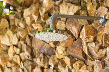 Doğal bir taş duvarla çevrili rahatlatıcı bir açık hava duşu. Rahatlama ve gençleşme için özel bir dinlenme yeri sağlıyor..