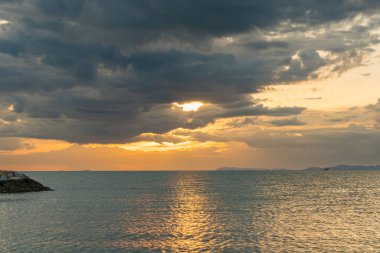 Okyanus batan güneşi nazikçe kucaklıyor, sıcak renkler gökyüzüne ve suya yayılıyor, sakin bir manzara yaratıyor..