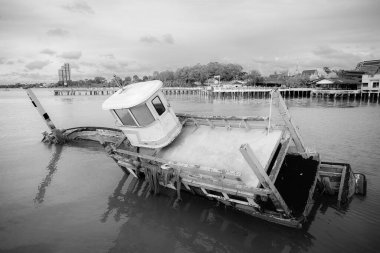 Chonburi, Thailand - May, 26, 2024 : Abandoned Fishing Boat Sinking in Harbor in sunset at Chonburi, Thailand.Black and white photo clipart