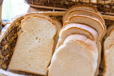 Hasır sepetin yakın çekimi taze pişmiş ekmekle dolu, farklı doku ve renkler sergileniyor..