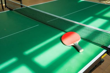 Red and black table tennis rackets with orange balls on a green table, ideal for indoor play. clipart