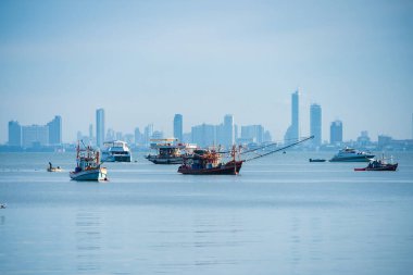 Chonburi, Thailand - May, 27, 2024 : Industrial Vessels on Tranquil Waters Before an Expansive Cityscape at Chonburi, Thailand clipart