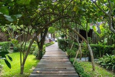 Chonburi, Tayland - 27 Mayıs 2024: Çonburi, Tayland 'da büyüleyici bir kemer yolu olan Verdant Garden' dan geçen tahta bir yol
