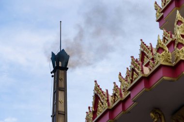 A view of smoke rising from a cremation chimney, symbolizing the end of life and spiritual release in Thai funerals. clipart