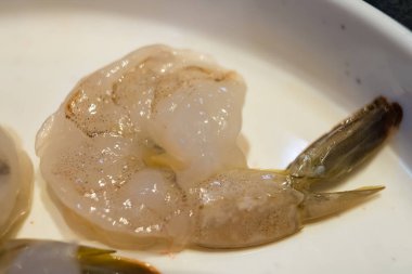 Yeni soyulmuş, kuyruğu sağlam, canlı rengini ve dokusunu vurgulayan karidesin yakın çekimi aşçılık meraklıları, yemek fotoğrafçıları ve deniz ürünleri temalı projeler için mükemmeldir..