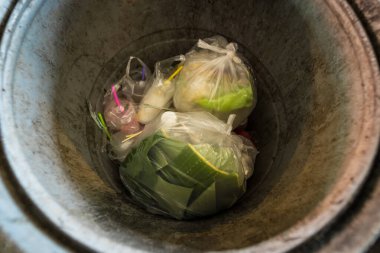 Yiyecek konteynırları ve plastik eşyalarla dolup taşan çöp kutusu, kentsel atık krizini vurguluyor.