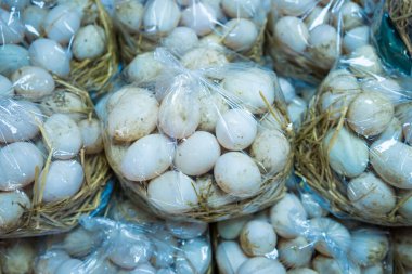 A vibrant scene capturing fresh duck eggs carefully packaged in transparent plastic bags, highlighting the charm of traditional market shopping and local produce. clipart