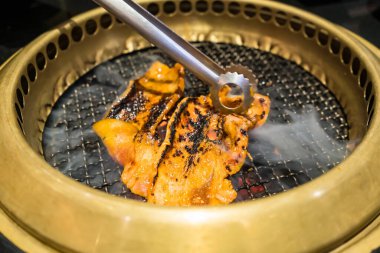 Izgara domuz eti, sebze ve erimiş peynirin yer aldığı lezzetli bir Kore barbekü partisi..