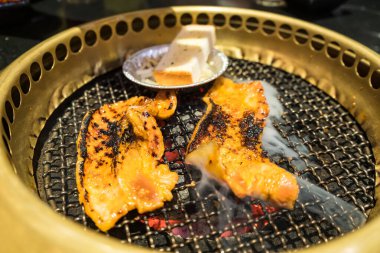 Izgara domuz eti, sebze ve erimiş peynirin yer aldığı lezzetli bir Kore barbekü partisi..