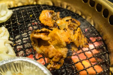 Izgara domuz eti, sebze ve erimiş peynirin yer aldığı lezzetli bir Kore barbekü partisi..