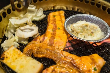 Izgara domuz eti, sebze ve erimiş peynirin yer aldığı lezzetli bir Kore barbekü partisi..