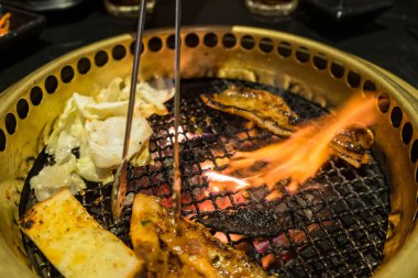 Izgara domuz eti, sebze ve erimiş peynirin yer aldığı lezzetli bir Kore barbekü partisi..