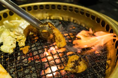 Izgara domuz eti, sebze ve erimiş peynirin yer aldığı lezzetli bir Kore barbekü partisi..