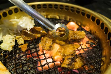 Izgara domuz eti, sebze ve erimiş peynirin yer aldığı lezzetli bir Kore barbekü partisi..