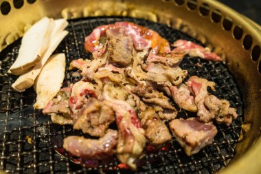 Izgara domuz eti, sebze ve erimiş peynirin yer aldığı lezzetli bir Kore barbekü partisi..