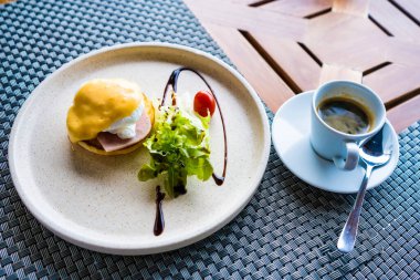 Jambonlu Benedict usulü yumurta, Hollandaise sosu ve yanında taze salata olan gurme kahvaltı tabağı..