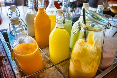Taze sıkılmış meyve suları cam şişelerde servis edilmeye hazır. Bu canlı, doğal içecekler su ve sağlıklı bir yaşam için mükemmeldir..