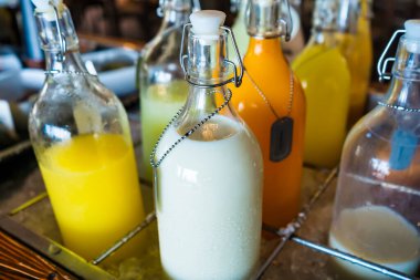 Taze süt ve taze sıkılmış meyve suyu servis edilmeye hazır cam şişelere dolduruldu. Bu sağlıklı ve ferahlatıcı içecekler harika bir tat ve doğal besinle birleşir..