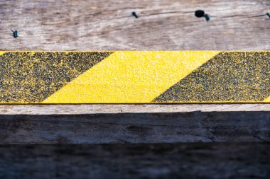 Tahta zeminlere uygulanan kayma önleyici bant işyerlerinde güvenliği sağlıyor, kaymaları ve düşmeleri önlüyor ve güvenli ortamları destekliyor..